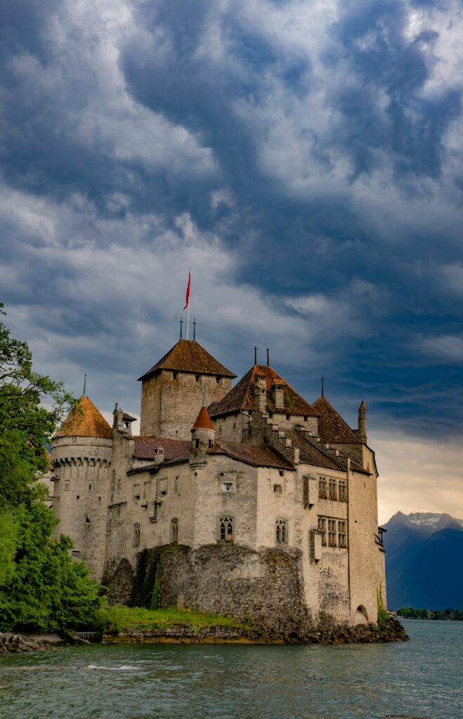 Chillon Castle on the shores of Lake Geneva under dramatic cloudy skies, capturing Swiss historical architecture.