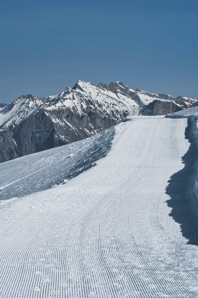 Freshly groomed ski slopes in the Alps, a prime destination for best winter vacations with snow, offering stunning views and perfect conditions for skiing enthusiasts.